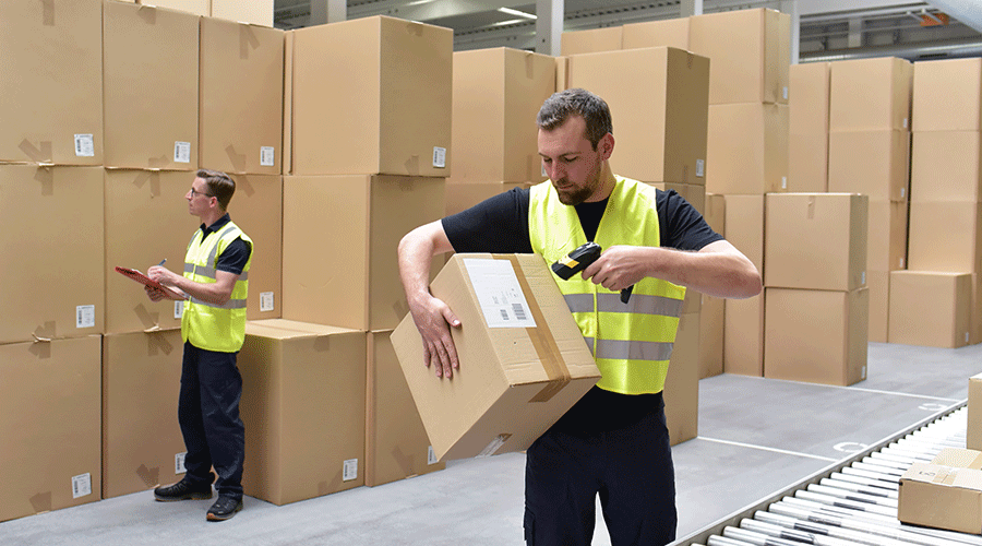 A warehouse worker lifts and scans a box.