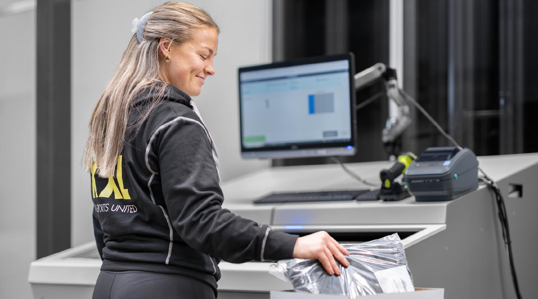 Happy female warehouse worker picking items next to a fusion port workstation