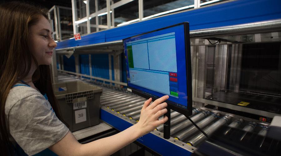 A warehouse worker in Decathlon clicking a screen while fulfilling an order with the AutoStore system