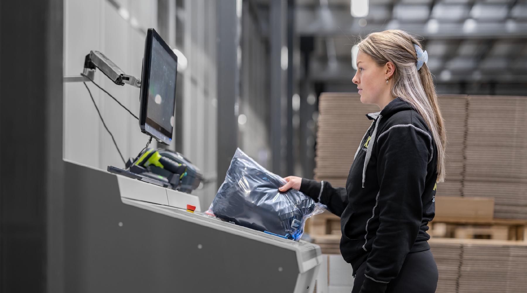 A female warehouse worker at an AutoStore workstation in an automated warehouse