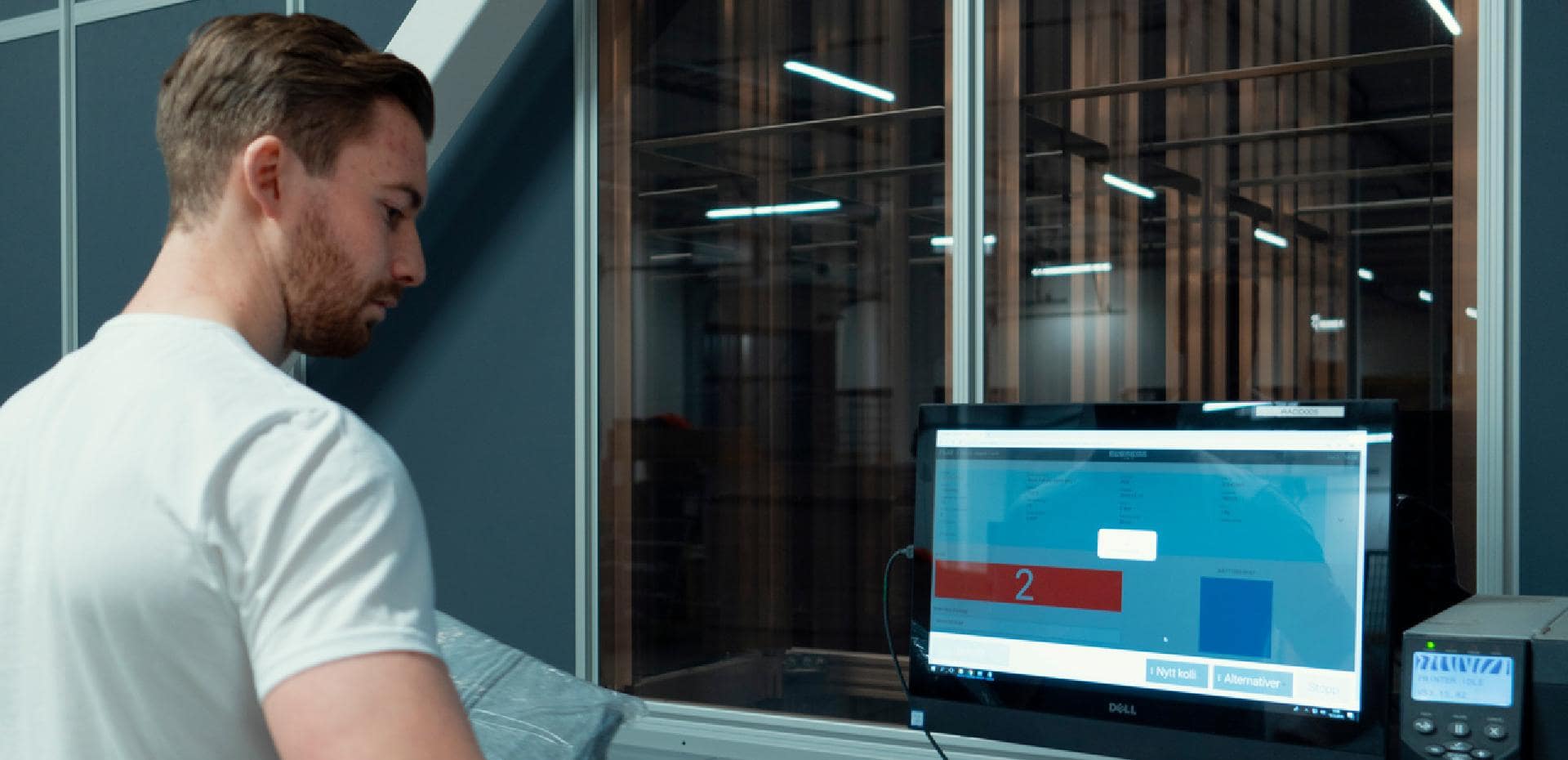 A worker next to a WMS system in an AutoStore