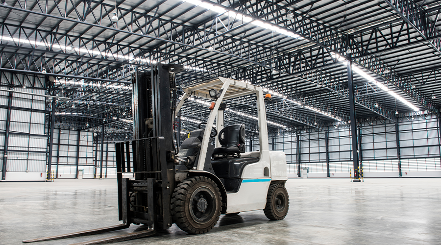A forklift parked within an empty warehouse. Image. 
