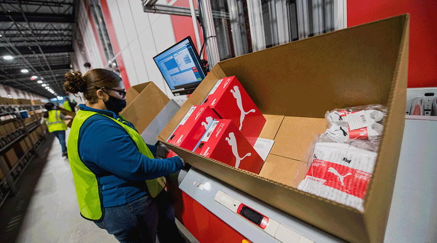 A worker picking and packing items from an AutoStore Port at PUMA in Indiana. Image.