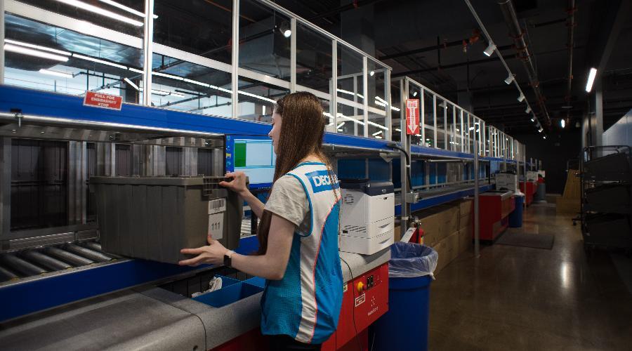 A female warehouse worker next to an AutoStore material handling system