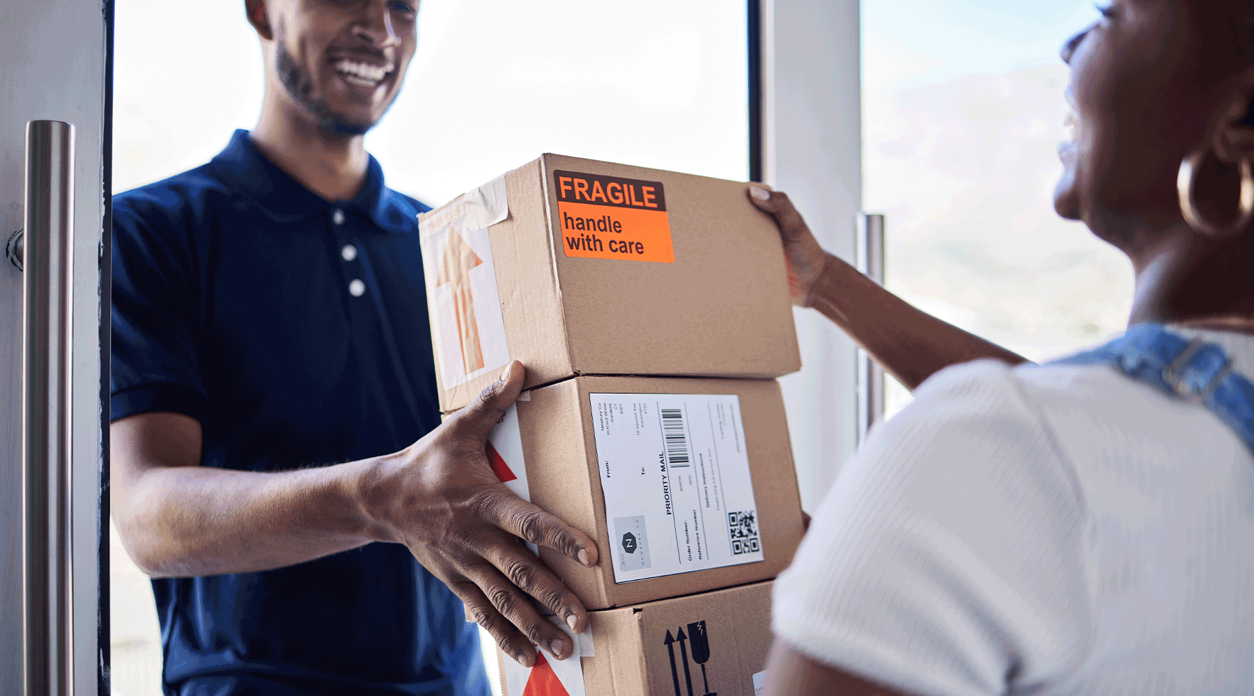 Man delivering three packages to woman. Image